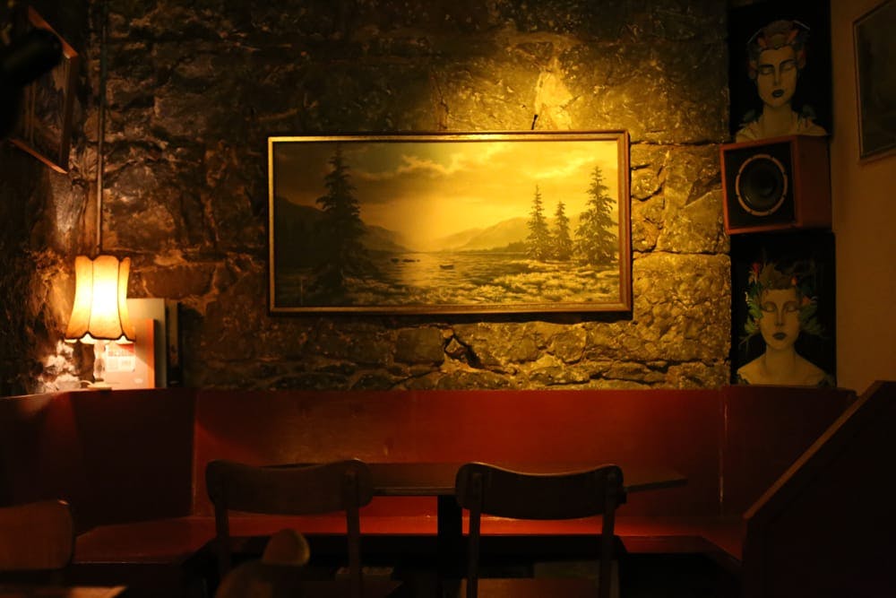 Image of warm red wooden booth with lamps and an old landscape painting.